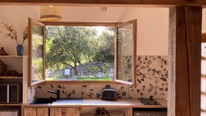 Una cocina con un ventanal grande, vigas de madera, un fregadero, un tostador y una lavadora.