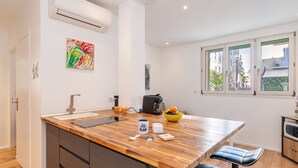 A modern kitchen with a wooden island, a coffee machine, and a bowl of fruit.