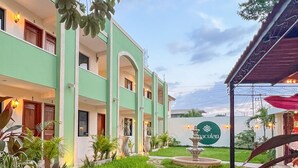 A hotel with a green facade, a stone pathway, and a sign reading "Maculan." - Hotel Maculan (Valladolid)