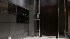 Un ascenseur moderne doté d’un écran numérique, d’une porte métallique et d’un escalier menant à un palier.
