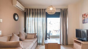 Un salon moderne avec un canapé, un téléviseur posé sur un meuble en bois et une grande fenêtre avec des rideaux.