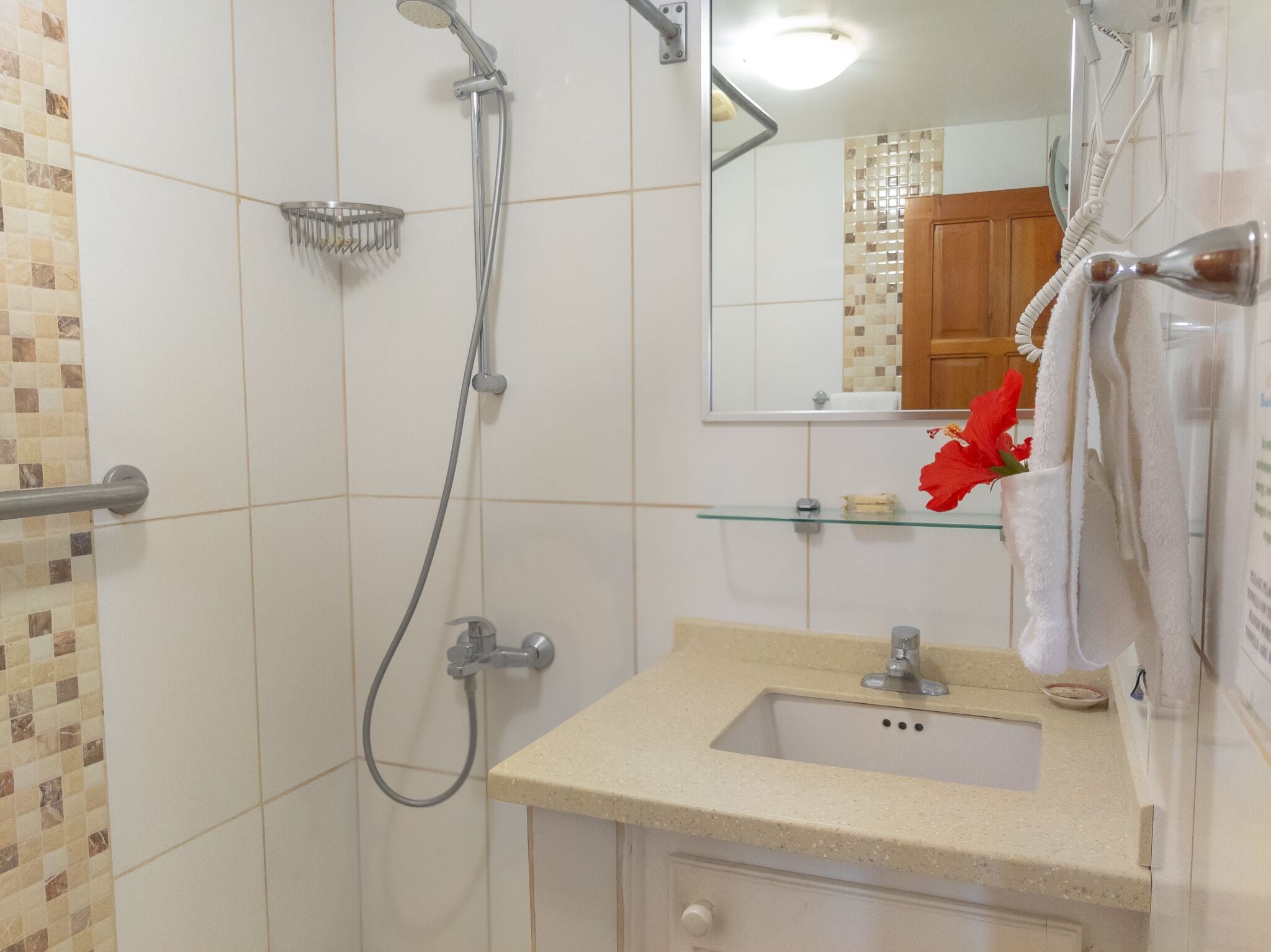 A bathroom with a shower, sink, and mirror.