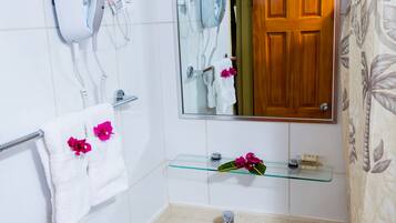 A bathroom with a white sink, a mirror, a towel rack with towels, a hairdryer, and a shower curtain.