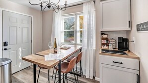 A modern kitchen with a dining table, chairs, a chandelier, a coffee machine, and a window with blinds. - Newly Renovated - Must Stay at in Algoma (Algoma)