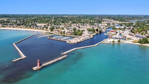 An aerial view of a coastal town with a marina, a lighthouse, and a mix of residential and commercial buildings. - Across the Street From Von Stiehl-newly Renovated (Algoma)