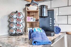 A kitchen with a coffee maker, a coffee pod holder, and a knitted item on the counter. - Newly Renovated-across the Street From Von Stiehl (Algoma)
