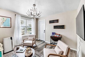A living room with a fireplace, a chandelier, a television, and a view of the outdoors. - Walking Distance to Everything- Newly Renovated (Algoma)