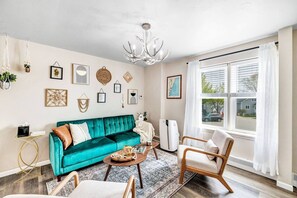 A living room with a teal sofa, a wooden coffee table, and a chandelier. - Walking Distance to Everything- Newly Renovated (Algoma)