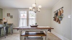 Een keuken met een rustieke houten tafel, een kroonluchter en een hangende pannendrager.