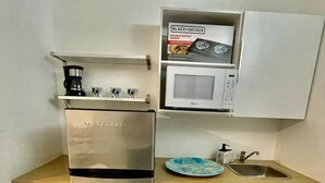 A compact kitchen with a stainless steel refrigerator, a microwave, a coffee maker, and a sink.