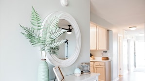 Un meuble blanc avec un miroir, un tableau encadré et une plante verte.