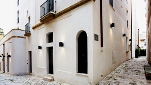 Una estrecha calle adoquinada con edificios blancos, puertas arqueadas y balcones.