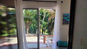 Habitació amb porta corredissa de vidre que dona a zona exterior amb terrassa i un gos petit.