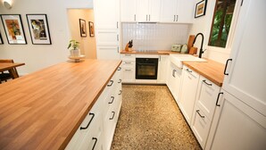 A modern kitchen with white cabinets, a granite countertop, and a built-in oven. - Sanctuary 33 - Your private haven near the river (Bright)
