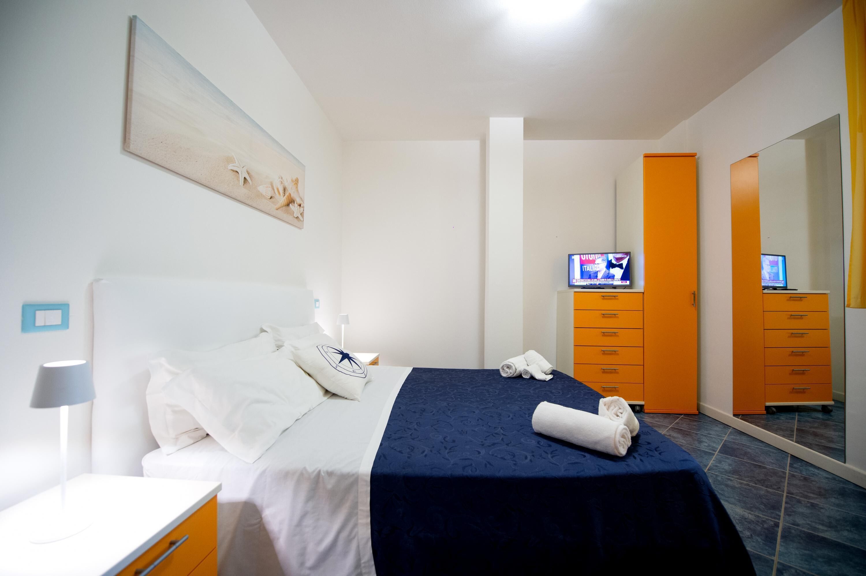 Een hotelkamer met een bed, een televisie, een kledingkast en een spiegel.
