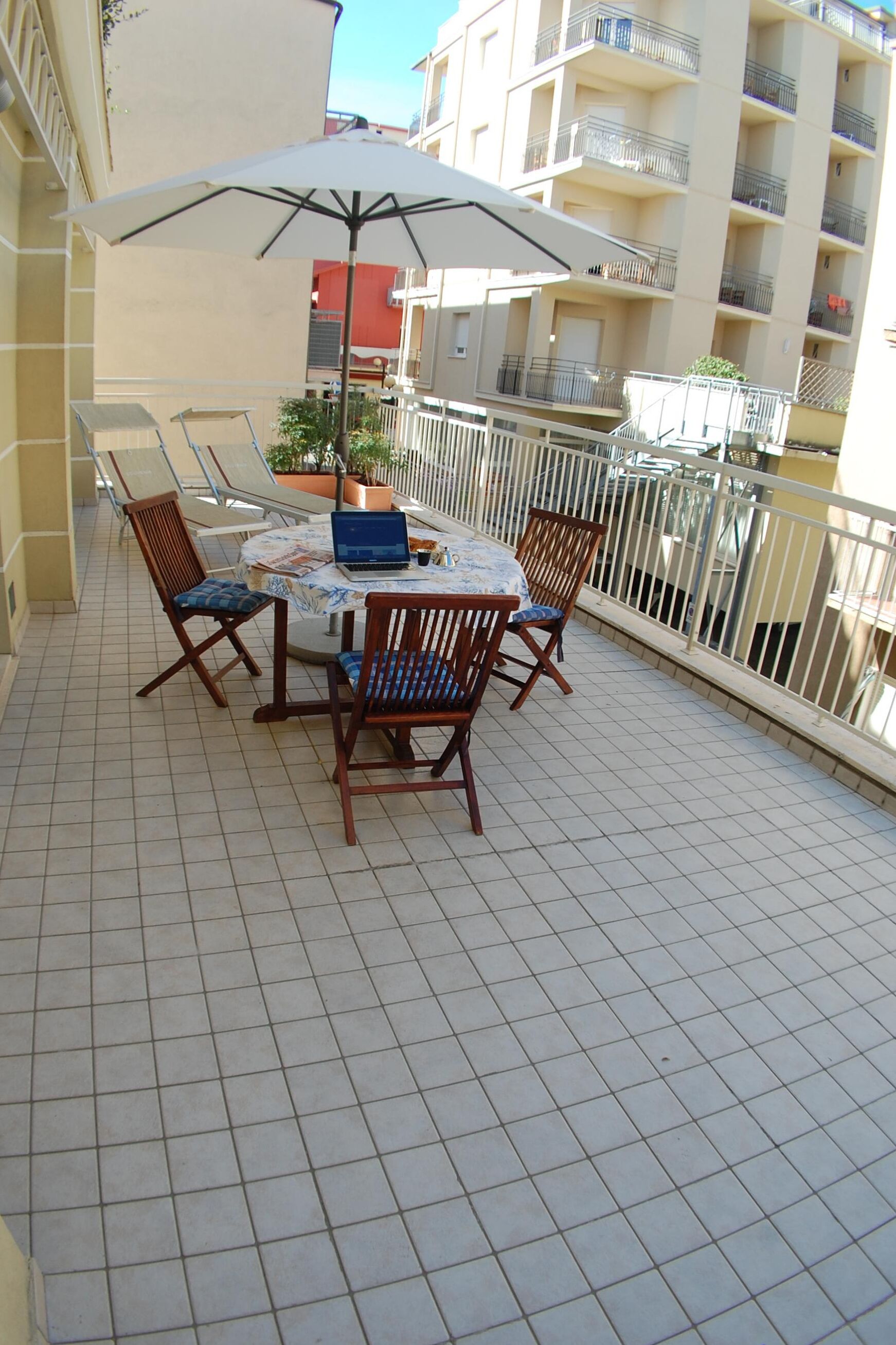 A balcony with a table, chairs, and a laptop.