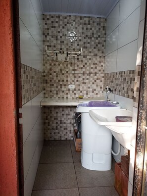 Un baño pequeño con salpicadero de azulejos, un lavabo blanco y una zona de ducha.