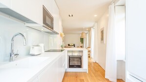 Una cocina moderna con armarios blancos, un lavaplatos de acero inoxidable, un microondas y un horno.