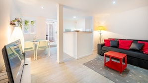 A modern living room with a black sofa, red cushions, a red coffee table, and a dining area with a table and chairs. - GuestReady - Delightful getaway in the city centre (Lisbon)