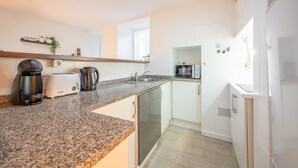 A modern kitchen with a granite countertop, a coffee maker, a toaster, and a microwave. - GuestReady - Delightful getaway in the city centre (Lisbon)