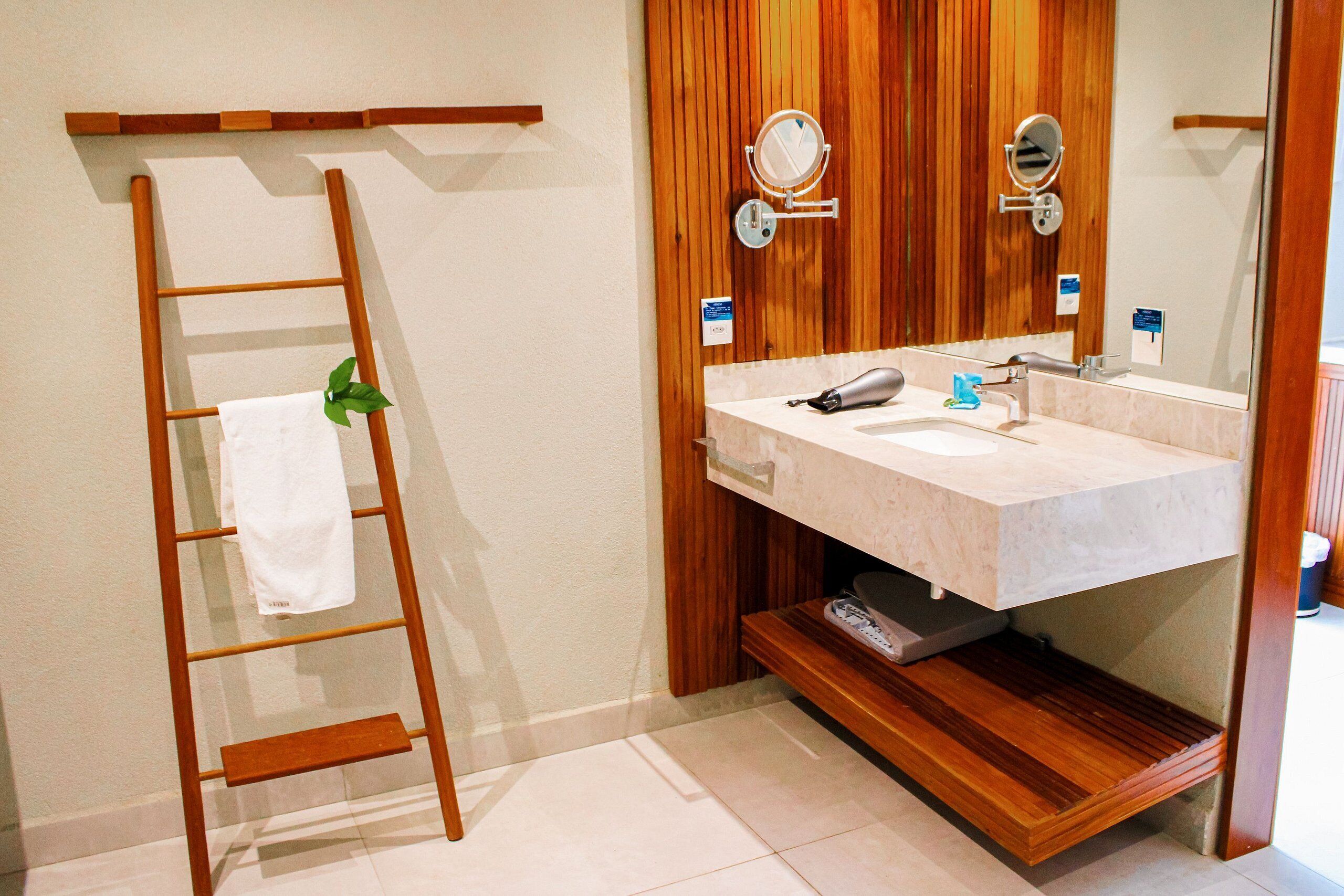 Une salle de bain avec une échelle en bois, un lavabo et deux miroirs.