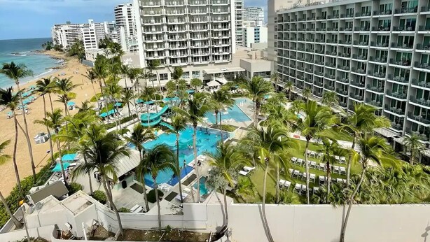 Um hotel com área de piscina, praia e estacionamento.