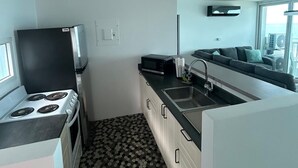 Uma cozinha compacta com fogão, micro-ondas, pia e uma janela ampla com vista.