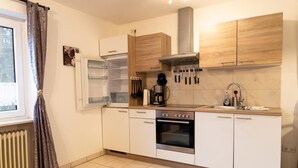 A modern kitchen with white cabinets, a built-in oven, and a stainless steel range hood. - Reiterhof Finkenmühle Fewo Gipsy (Weißenstadt)