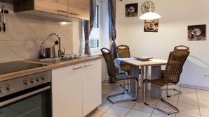 A kitchen with a stove, sink, and dining table with chairs. - Reiterhof Finkenmühle Fewo Gipsy (Weißenstadt)
