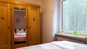 Un dormitorio con cama, armario y ventana con vistas a árboles.