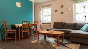 Una sala de estar con un sofá, una mesa de centro y dos sillas de madera.