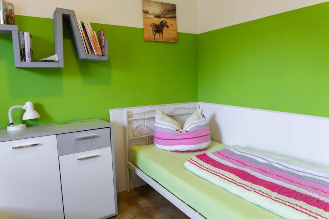 Une petite pièce aux couleurs vives, avec un lit, un bureau et des étagères.