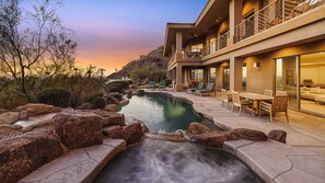 A modern house with a swimming pool, outdoor furniture, and a view of the surrounding landscape.