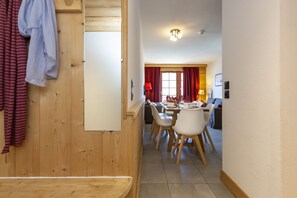 A wooden interior with a dining area, a whiteboard, and a red curtain. - Residence Odalys Les Fermes De Chatel (Chatel)