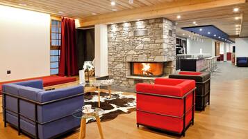 Un salon moderne avec une cheminée en pierre, des canapés rouges et bleus, et une table basse en verre.