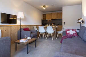 A modern living room with a sofa, a coffee table, and a dining area with chairs and a table.