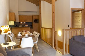 Ein Essbereich mit einem Tisch für vier Personen, einer Lampe und einer Küche mit Holzschränken und Geräten.