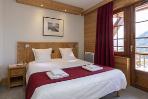 A bedroom with a wooden headboard, a bed with white bedding, a red throw blanket, and a framed picture on the wall.
