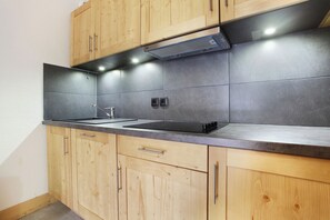 Een moderne keuken met houten kastjes, een zwart aanrecht en een ingebouwde kookplaat.