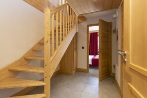 Una escalera de madera que conduce a un dormitorio con una cortina roja.