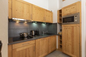 A kitchen with wooden cabinets, a microwave, a stove, and a sink. - Residence Odalys Les Fermes De Chatel (Chatel)