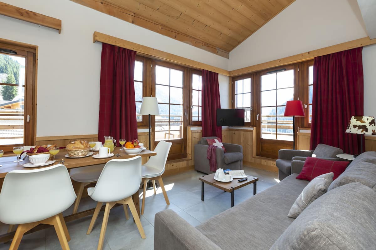 A spacious living area with a dining table, chairs, a sofa, and a television.