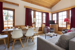 Un'ampia zona giorno con tavolo da pranzo, sedie, divano e televisore.