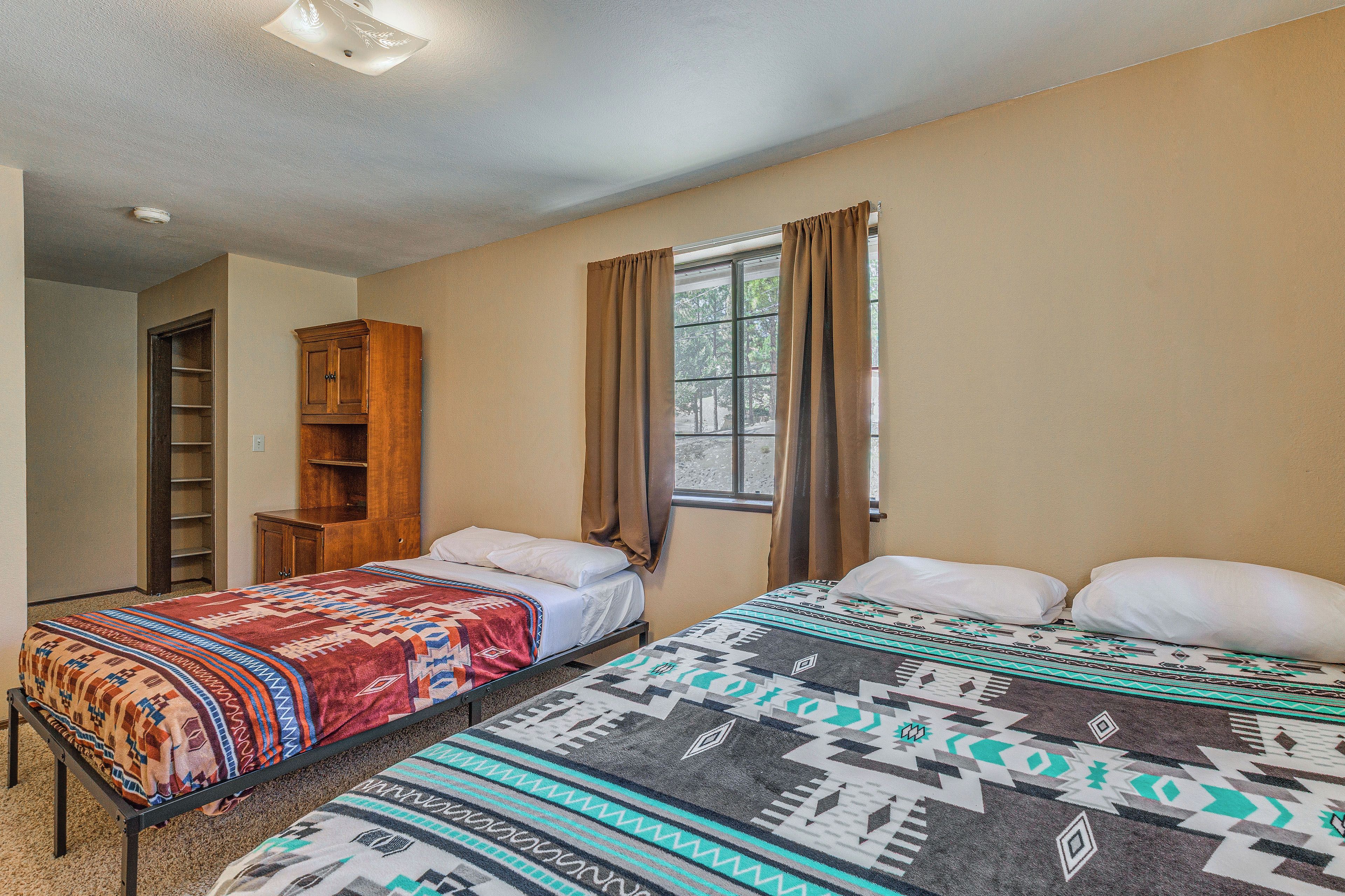 Een kamer met twee bedden, een houten kast, een raam met gordijnen en een plafondlamp.