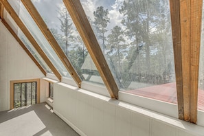 A room with skylights, wooden beams, and a view of trees.