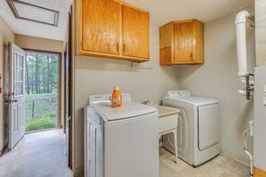 A laundry room with two washing machines, wooden cabinets, and a door leading to a view of trees. - Ruidoso Retreat w/ Grill ~ 3 Mi to Grindstone Lake (Ruidoso)