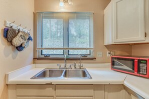 A kitchen with a double sink, a microwave, and a window with blinds. - Ruidoso Retreat w/ Grill ~ 3 Mi to Grindstone Lake (Ruidoso)