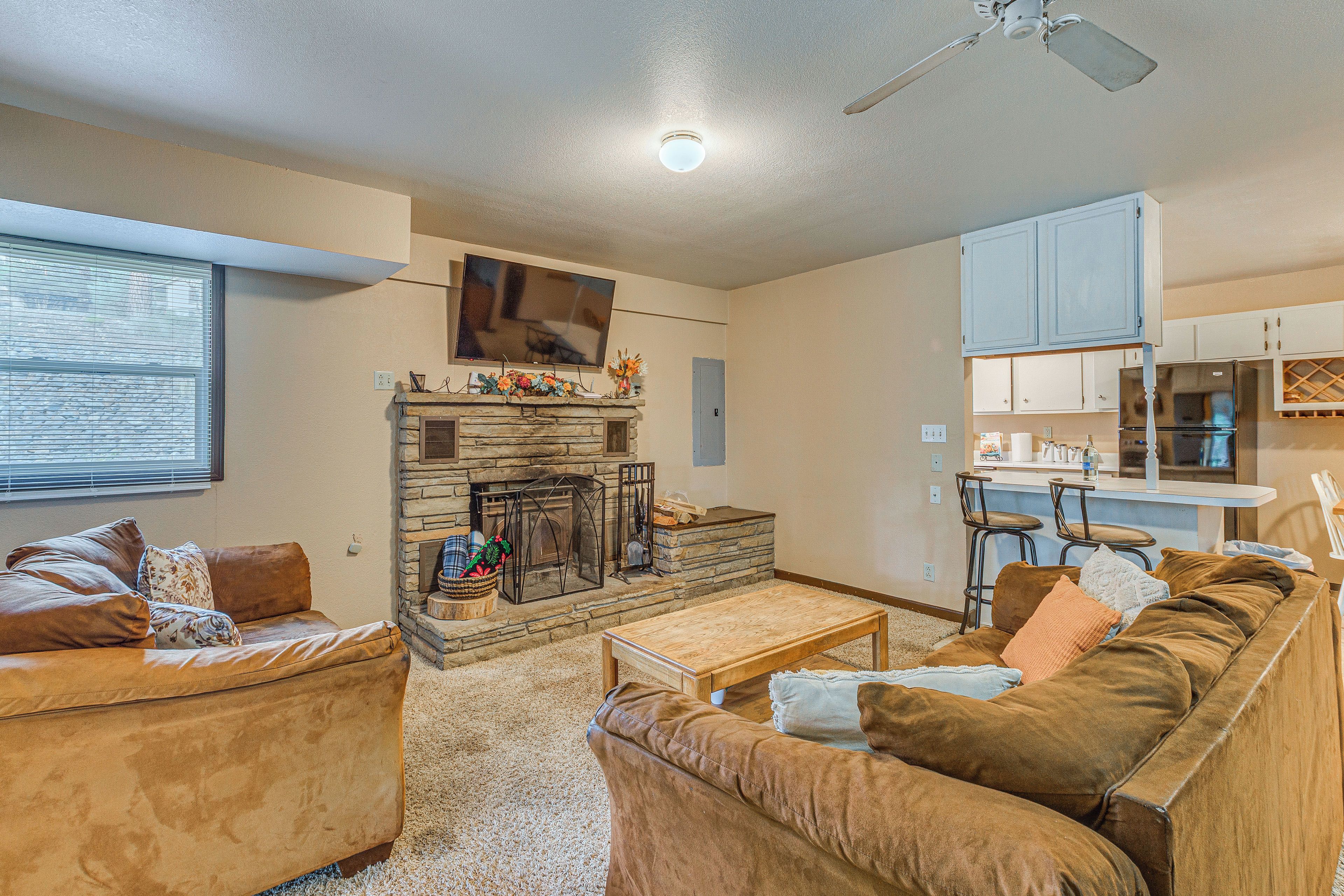 A living room with a fireplace, a television, and a kitchen area with bar stools.