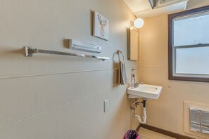 Un baño con lavamanos blanco, toallero y un cuadro en la pared.