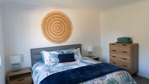Ein Schlafzimmer mit Bett, Nachttisch, Kommode und Wandbild.